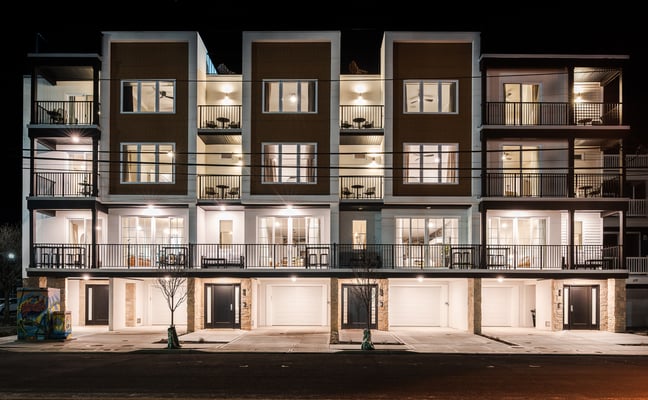Modern multi-unit Jersey Shore property lit up at night with balconies and large windows