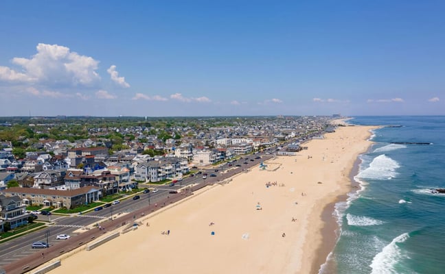 Aerial view of the Jersey Shore coastline with sandy beach, ocean waves, and residential homes stretching into the distance